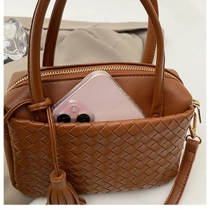 Close-up of brown woven leather bag showing storage capacity with a mobile phone inside