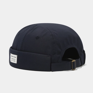 Détail du bonnet docker bleu marine avec étiquette tissée et sangle à boucle métallique