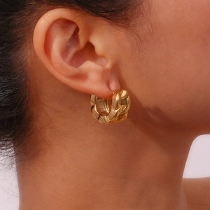 Close-up of a gold chunky chain link hoop earring worn on a model's ear