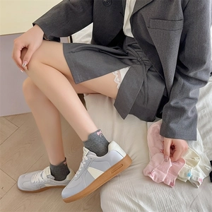 Close-up of low-cut cotton socks with bow embroidery worn with casual sneakers