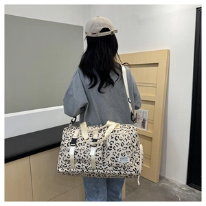 Macro shot of leopard print travel bag with multiple pockets and adjustable strap on a model