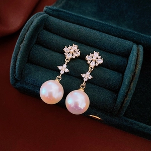 Detail of luxury pearl and diamond flower earrings inside a green velvet jewelry box