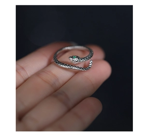 Macro detail of silver snake ring featuring green gemstone eyes and intricate scale textures
