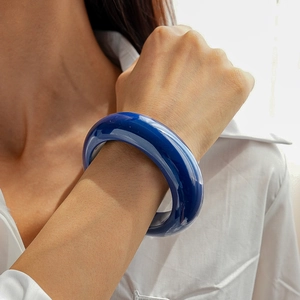 Gros plan d'un bracelet rond géométrique en résine bleu foncé porté par un mannequin