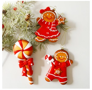 Detail of gingerbread man and lollipop ornaments hanging on green pine branches