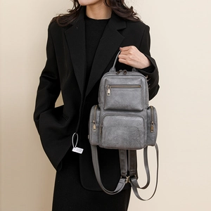 Close-up of gray vintage PU leather backpack with multiple zippers worn by model