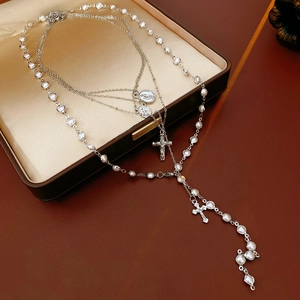 Detail of multi-layer silver pearl necklace with cross pendant in a jewelry box