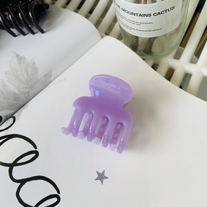 Macro view of purple glossy hair claw clip with interlocking teeth on an open book