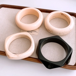 Détail de bracelets géométriques en acrylique de formes rondes et carrées sur un plateau