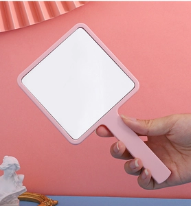 Detailed close-up of a pink square handheld cosmetic mirror with a plastic frame and handle