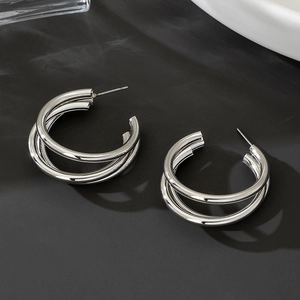 Detailed view of silver double hoop C-shaped earrings on a textured black background