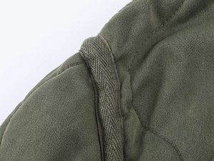 Detail view of military green jacket shoulder seam with woven rope decoration and twill fabric