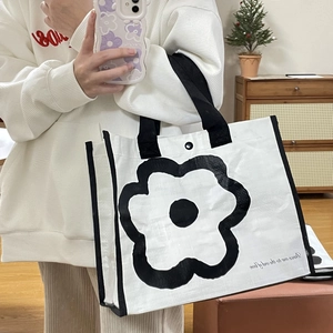 Detailed view of white woven tote with large black floral print and nylon handles