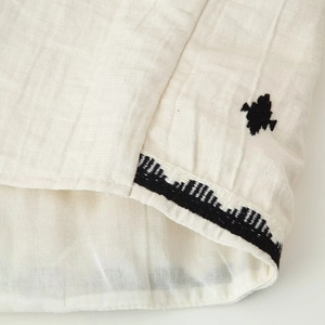 Detail of linen cotton set featuring black embroidery and tassel tie texture