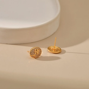 Close-up of gold-plated oval stud earrings with flower engraving and zircon pave crystals