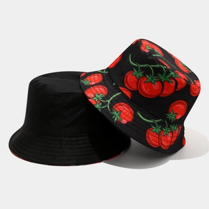 Detail showing reversible bucket hat with solid black side and vibrant red tomato pattern