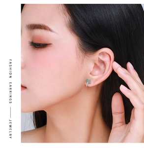 Model wearing silver coconut tree stud earrings with sparkling green crystal stones