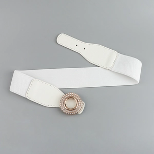 Detail of white elastic waist belt featuring a gold round buckle with sparkling rhinestones