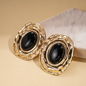 Close-up of vintage oval earrings with gold hammered edges and black resin inlay