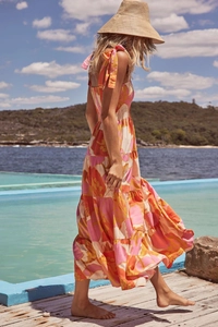Detail of vibrant floral print dress with thin straps against a coastal background