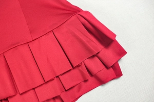 Detailed view of layered red ruffled hem and fine stitching on a sleeveless dress