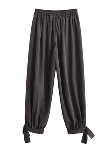 Detail of dark grey loose trousers with elastic high waist and bow-knot cuffs