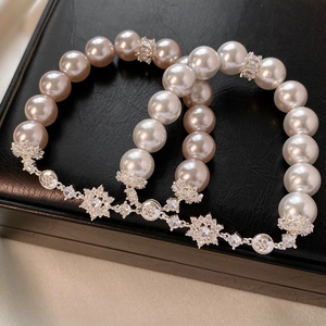 Détail de bracelets en perles avec breloques fleurs en zircon et perles polies