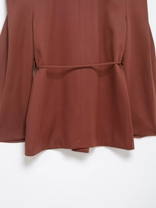 Close-up of a brown-red belted waist detail on a minimalist women's blazer