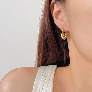 Gros plan de boucles d'oreilles cœur dorées sur un modèle avec une finition polie chic