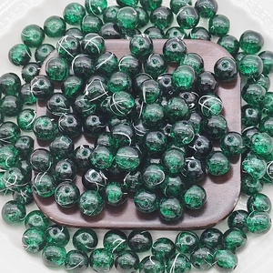 Close-up of 10mm green cracked glass beads for DIY jewelry making on a dark wood block