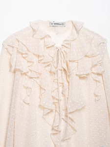 Detailed close-up of ruffled beige chiffon blouse neckline with delicate tie-up design