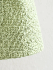 Detailed macro view showing texture of light green tweed fabric and garment hem finish