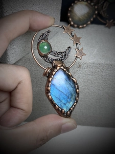 Detail of handmade copper wire-wrapped pendant with labradoreite moon and star design