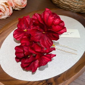 Close-up of red fabric flower hair pin with golden U-shaped metal clips for styling