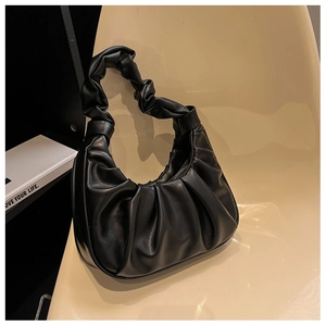Close-up of the elegant black pleated leather texture on a stylish underarm bag