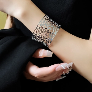 Detail of a wide hollow silver bangle showing the irregular curved surface on a wrist