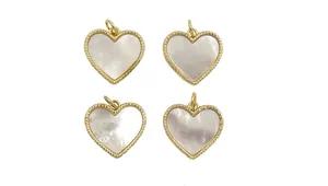 Close-up of four golden heart shell pendants with beaded edge for DIY jewelry
