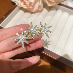 Detailed close-up of sparkling gold star hair clips with crystals on velvet background