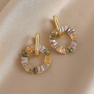 Detailed view of gold hoop earrings with multi-colored crystals on beige silk fabric