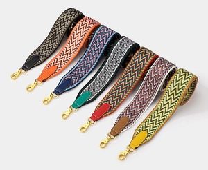 Detailed view of colorful woven bag straps with leather ends and gold metal buckles