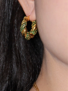 Detail of twisted 18K gold stainless steel earrings with green zircon on a model