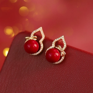 Macro view of gold hollow gourd studs with red beads and sparkling white zircons