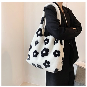 Detail of soft white plush tote bag with black flower patterns on a shoulder strap