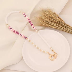 Detail of bohemian beaded phone strap with pink striped beads and golden heart clasp