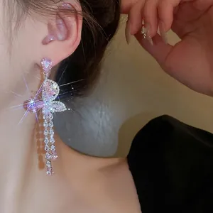 Boucles d'oreilles papillon à pompons en zircon rose avec aiguilles en argent sur mannequin