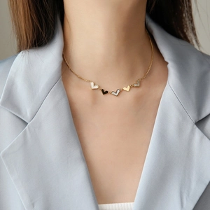 Elegant 18K gold stainless steel necklace with white shell heart pendants on a model