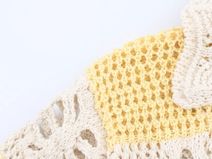Macro detail of diamond mesh crochet texture in light yellow and cream knit fabric