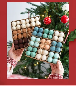 Close-up of handmade wool felt balls in gift boxes held before a decorated Christmas tree