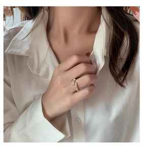 Detailed view of a gold bamboo-style ring with micro-set zircons on a model's finger