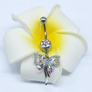 Macro shot of a colorful bow pendant belly button ring on a plumeria flower
